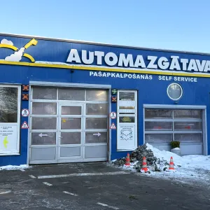 Automa&scaron;īnas mazgātava ar zilu fasādi un slēgtām garāžas durvīm.