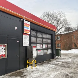 Automātiskā automazgātava ziemas dienā, ēkai ir sarkans jumts.