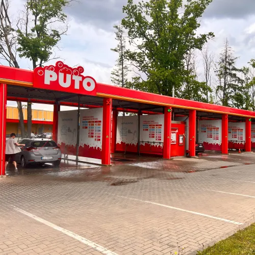 Automa&scaron;īnu mazgātuve ar sarkanām būdām un norādi "Puto" uz jumta.