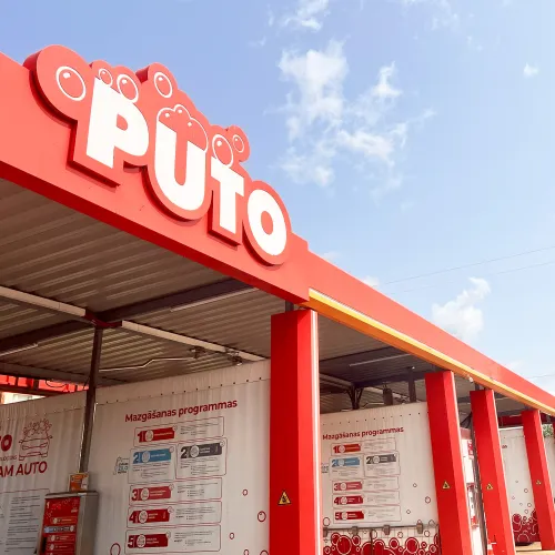 Sarkanas automazgātuves ēka ar zilu debesu fonu.