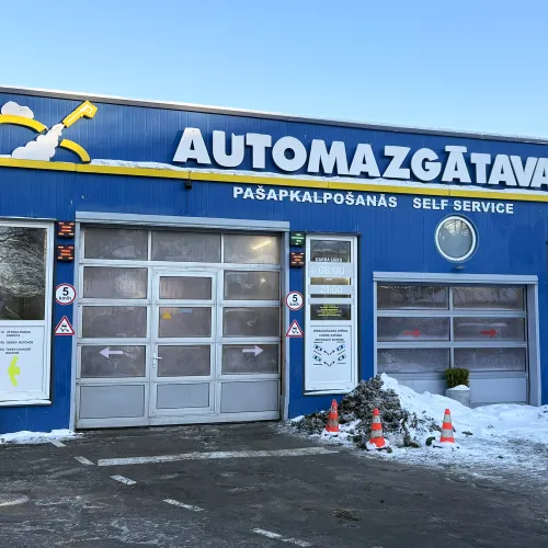Automa&scaron;īnas mazgātava ar zilu fasādi un slēgtām garāžas durvīm.
