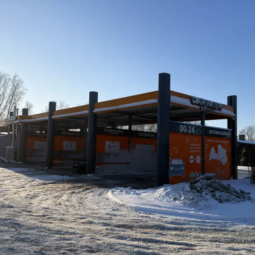 Pa&scaron;apkalpo&scaron;anās automazgātava sniegotā ainavā, oranži un melni toņi.