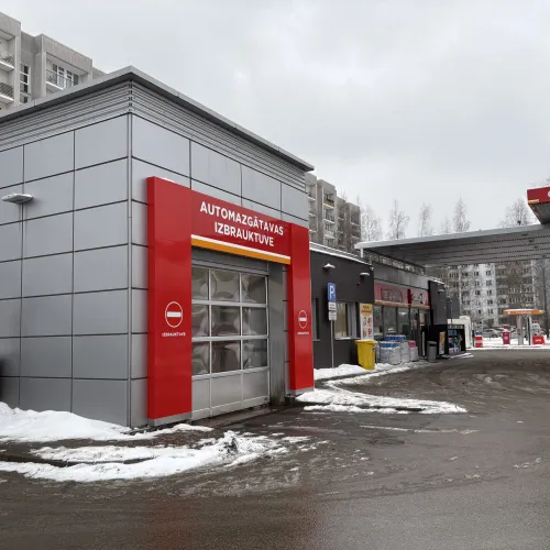 Automa&scaron;īnu mazgātava ar sarkanu fasādi sniegotā pilsētā.
