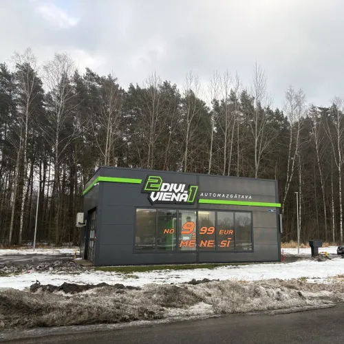 Pelēka automazgātava meža malā, ziemas ainava.