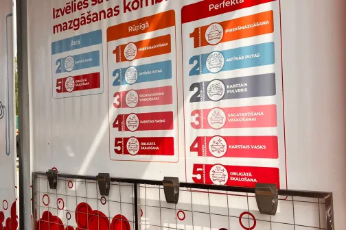 Stenda siena ar sarkaniem un baltiem grafiskiem elementiem.