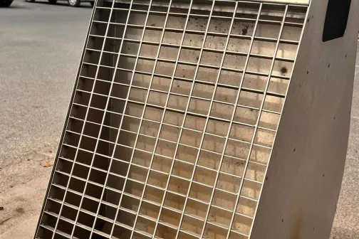 Nerūsējo&scaron;ā tērauda restes stāv uz ietves.