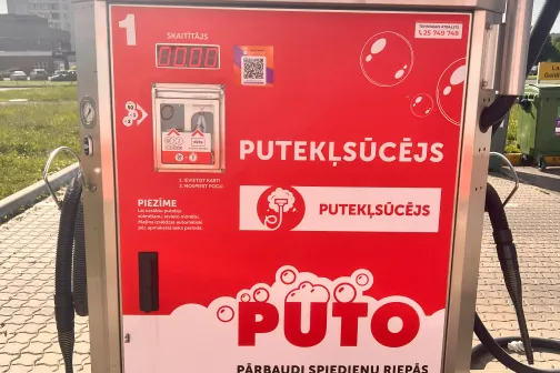 Putekļsūcēja automāts ar sarkanu reklāmu ārpusē.