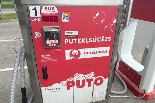 Putekļsūcēja automāts ar sarkanām detaļām un &scaron;ļūteni.