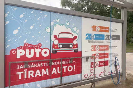 Mazgātavas reklāma ar sarkanu auto, putām un ērtās mazgā&scaron;anas norādēm.