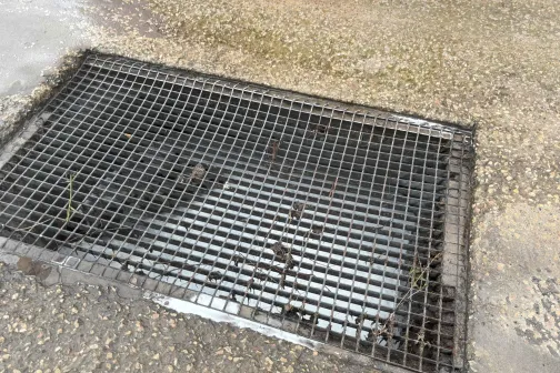 Metāla restes uz betona virsmas ar ieplūdumu.