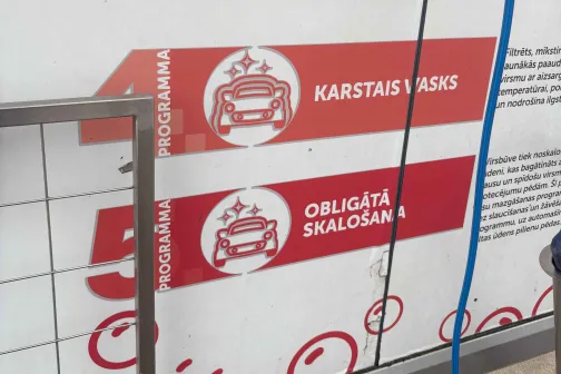 Sarkani un balti norādījumi automazgātavā uz sienas.