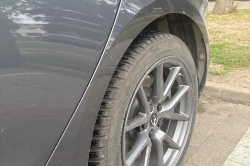 Tum&scaron;as krāsas automa&scaron;īnas aizmugurējais ritenis uz stāvlaukuma.