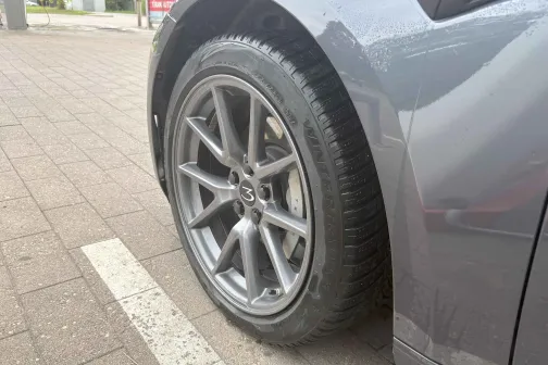 Pelēka automa&scaron;īna ar tīru riteni uz stāvlaukuma seguma.