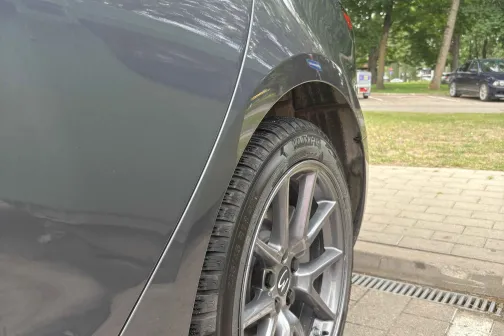 Tum&scaron;a automa&scaron;īna stāvvietā, redzams spīdīgs sāns un aizmugurējais ritenis.