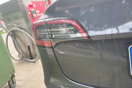 Automa&scaron;īnas aizmugure pie degvielas sūkņa blakus zaļam konteineram.