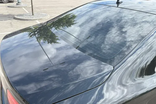 Atspulgi uz spīdīgas ma&scaron;īnas virsmas zem mākoņainām debesīm.