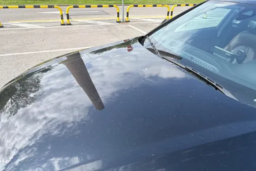 Melnas automa&scaron;īnas motora pārsegs ar atspulgiem.