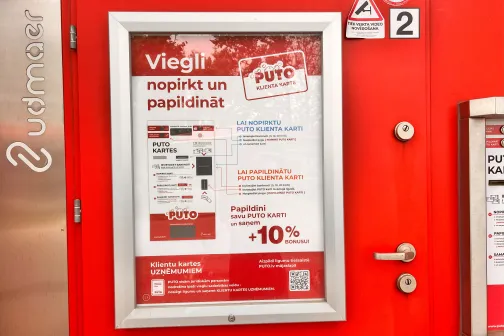 Sarkanas durvis ar reklāmas plakātu rāmī.