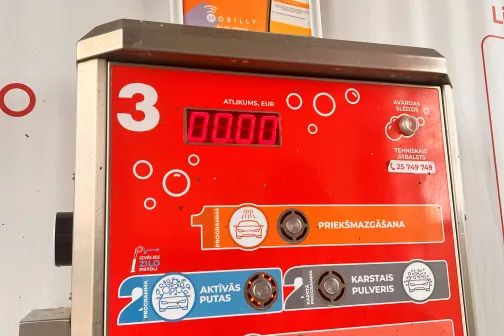 Sarkana pa&scaron;apkalpo&scaron;anās automazgātavas automāts ar ekrānu un pogām.