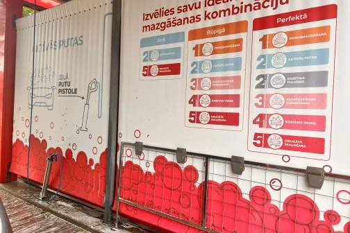 Balts siena stends ar mazgā&scaron;anas programmu tabulu un sarkaniem burbuļiem.