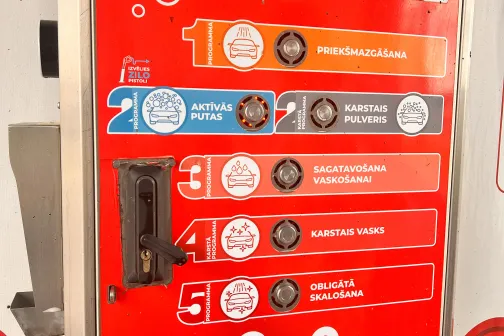 Automātu panelis ar sarkanu un baltiem elementiem.