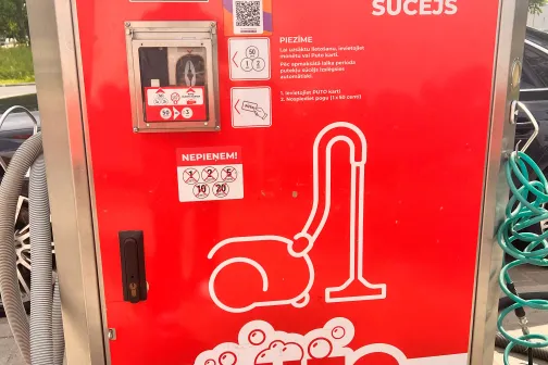 Putekļu sūcēja automāts ar sarkanu dizainu un norādēm.