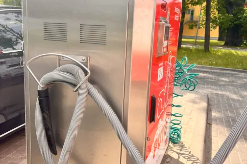 Pelēks un sarkans putekļusūcēja automāts ar vadiem.