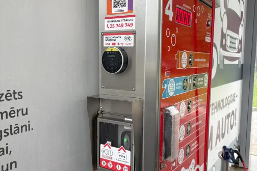 Automazgātuves maksājumu automāts ar sarkanām un sudraba detaļām.