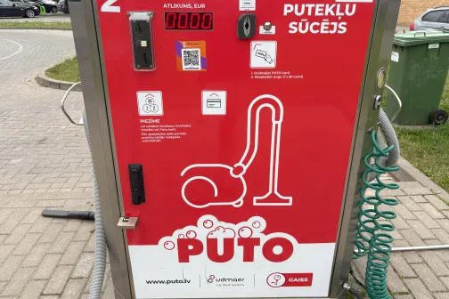 Putekļu sūcēja automāts ar sarkanu dizainu un &scaron;ļūteni.