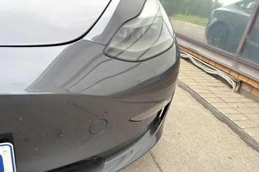 Pelēkas automa&scaron;īnas priek&scaron;ējais bampers pie stikla ēkas.