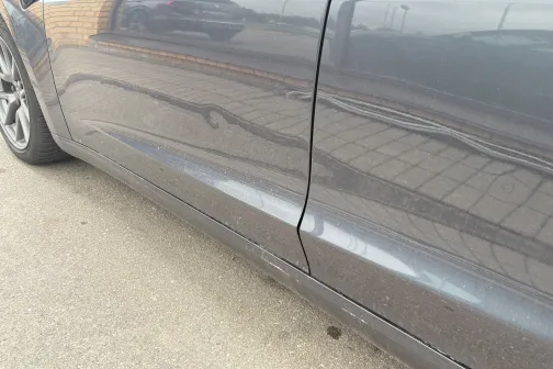 Tum&scaron;a automa&scaron;īnas sānmalas virsma, atspoguļo bruģakmeņus.