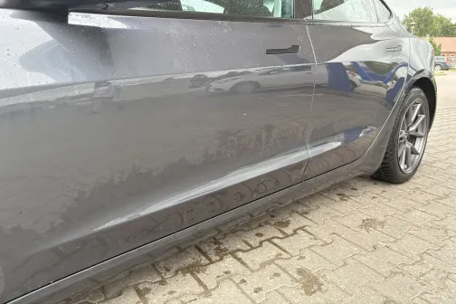 Pelēkas automa&scaron;īnas sānskats uz bruģa, nedaudz mitrs no mazgā&scaron;anas.