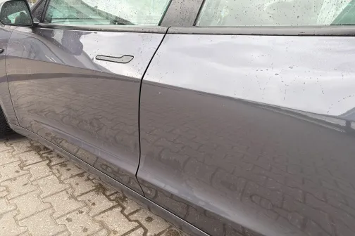 Pelēka automa&scaron;īna ar ūdens pilieniem uz jumta.