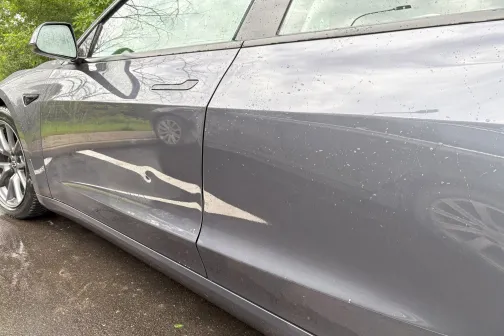 Tum&scaron;a automa&scaron;īna ar dažiem netīrumiem uz sāna, blakus zaļa vide.