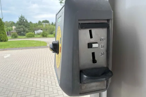 Monētu automāts automazgātavā ārā, blakus bruģētam segumam.