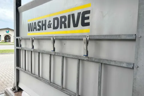 Metāla kāpnes pie sienas ar uzrakstu "WASH & DRIVE".