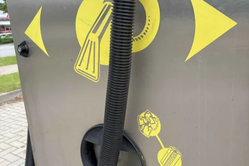 Metāla putekļsūcējs ar dzelteniem auto mazgātavas simboliem un &scaron;ļūteni.