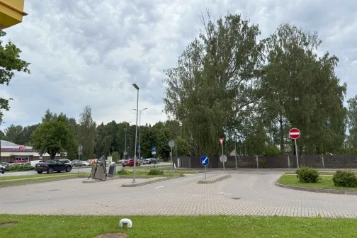 Autostāvvieta pie kokiem zem mākoņainām debesīm.