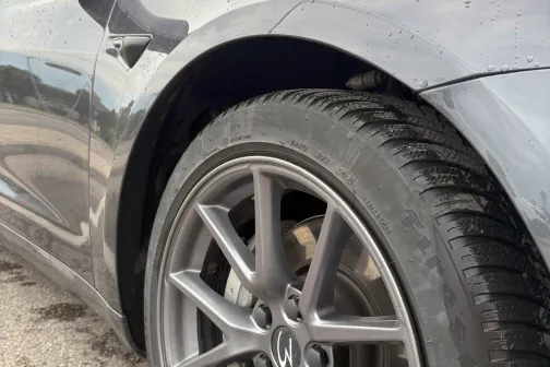 Pelēka automa&scaron;īna tuvplānā, redzams spīdīgais priek&scaron;ējais ritenis.