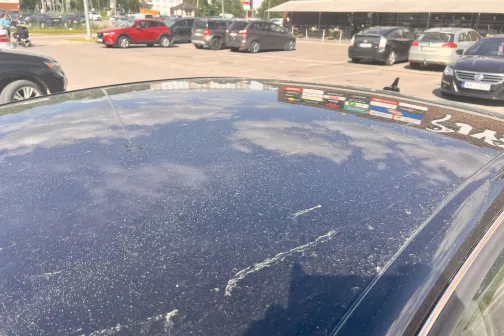 Auto jumts klāts ar putekļiem stāvvietā saulainā dienā.