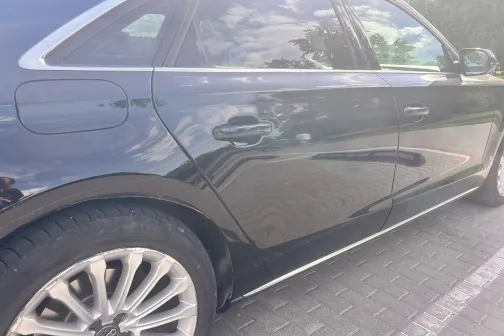 Melnas automa&scaron;īnas sānskats spīd saulē.