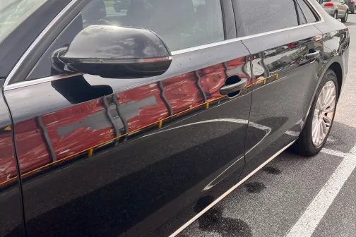 Melns automobilis novietots stāvvietā.