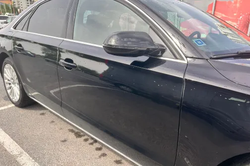 Melnas automa&scaron;īnas sānskats uz stāvlaukuma fona.