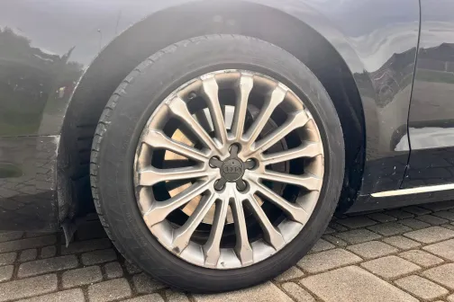 Auto ritenis ar sudrabainu disku uz bruģa.