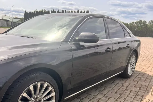 Tum&scaron;as krāsas sedans uz bruģēta ceļa saulainā dienā.