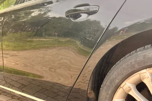 Melna automa&scaron;īna uz bruģēta ceļa, sānu skats.