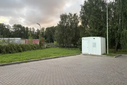 Autostāvvieta ar zaļojo&scaron;u apkārtni un mākoņainām debesīm.