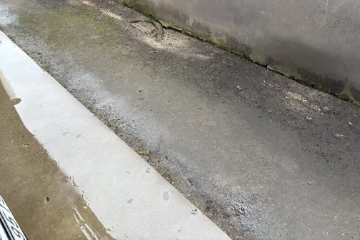 Mitrs, netīrs ceļa segums pie sienas.