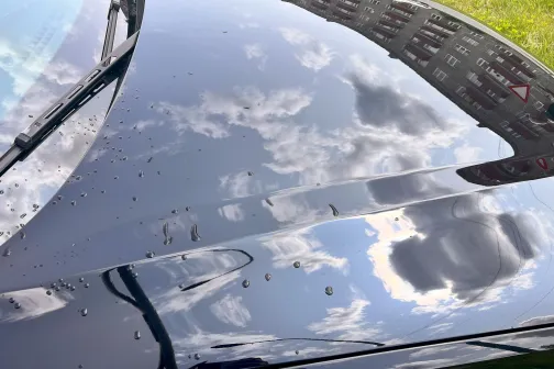 Automa&scaron;īnas pārsegs ar debesu atspulgu un mazām pilēm.