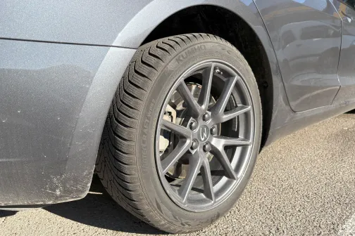 Sudrabains auto ritenis uz bruģa saules gaismā.